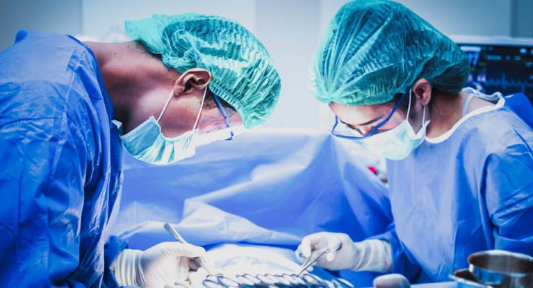 Eine Ärztin und ein Arzt mit Mundschutz sortieren chirurgische Instrumente vor einer Operation