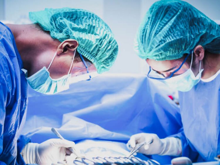 Eine Ärztin und ein Arzt mit Mundschutz sortieren chirurgische Instrumente vor einer Operation