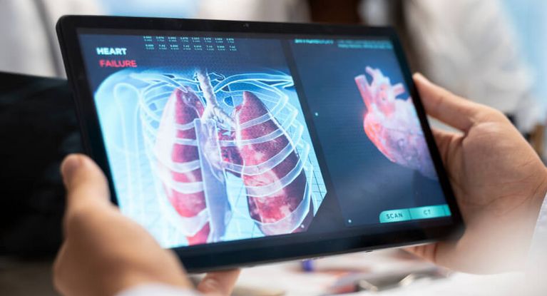 Arzt und Pflegekraft betrachten am Tablet eine Aufnahme eines Herzens