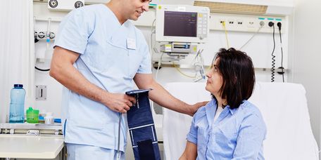 Pfleger bereitet Patienten auf Messung des Blutdrucks vor