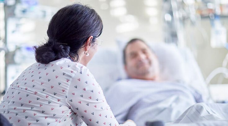 Ehefrau besucht Ehemann,der im Krankenbett liegt, im Krankenzimmer